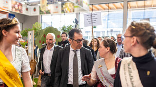 Cem Özdemir (M, Bündnis 90/Die Grünen), Bundesminister für Ernährung und Landwirtschaft, spricht während seines Besuchs der Messe Fruchtwelt Bodensee auf dem Gelände der Messe Friedrichshafen mit Sina Bernhard (2.v.r.), Bodensee-Apfelprinzessin 2022-2024.