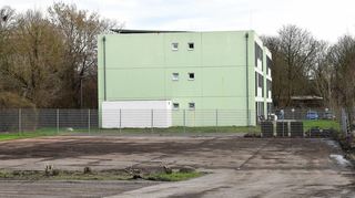 Der Standort für die geplante Asylbewerberunterkunft in der Wollstraße auf dem Parkplatz des Wertstoffhofs, hinten ein bestehendes Gebäude.