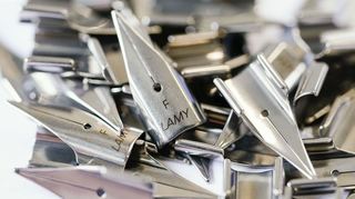 Federn für Füllfederhalter mit der Aufschrift "Lamy" liegen auf einem Tisch.