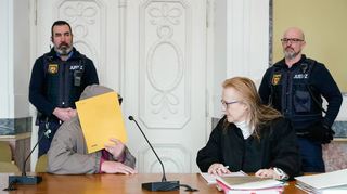 Der Angeklagte Arthur K. verbirgt im Missbrauchsprozess von Edenkoben sein Gesicht hinter einem Aktendeckel, als er mit seiner Verteidigerin Gabriele Haas spricht.