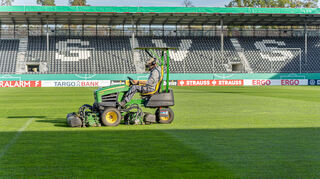 Mit dem Rasenmäher wird der Rasen im Fußballstadion gestutzt.