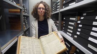 Elke Leinenweber zeigt im Magazin des Marchivums historische Viernheimer Zeitungen.