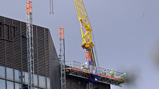 Die Arbeiter auf dem Dach warten, bis der Wind die Rückbau-Arbeiten zulässt.