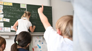 Schüler einer Grundschule arbeiten in einem Klassenzimmer an Mathematikaufgaben.