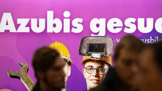 Besucher auf einer Jobmesse vor dem Schriftzug „Azubis gesucht“. Arbeitgeber locken die Schulabgänger mit höheren Löhnen.