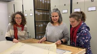 Elke Leinenweber (v.l.), Carmen Daramus und Julia Metz schauen sich im Lampertheimer Stadtarchiv einen Plan der Domkirche an.