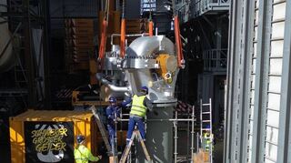 Noch hängt die neue Turbine an den Seilen des Schwerlastkrans – doch gleich ist das Einheben in die Anlage abgeschlossen.