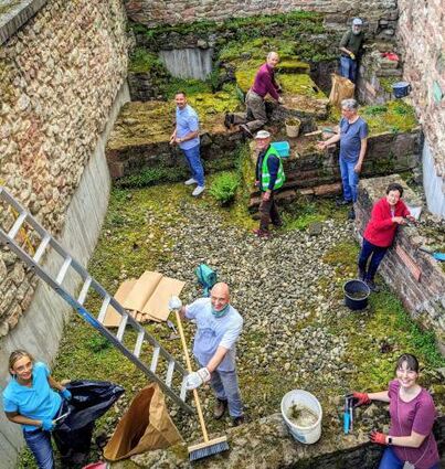 Freiwillige reinigen das archäologische Fenster am Bischofshof.