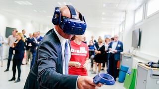 Brudermüller beim Testen einer Virtual-Reality-Brille mit BASF-Azubis.