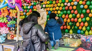 Kinder beim Ballonwerfen auf dem Frühjahrsmarkt. Wenigstens ist der Stand überdacht.