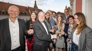 Anstoßen auf die Domförderung: Gerne genießen Dombauvereinsvorsitzender Dr. Gottfried Jung (v. l.), Weinprinzessin Laura Götze, Weihbischof Otto Georgens, Weinprinzessin Hanna Spies, Kellermeister Christian Anselmann, die Pfälzische Weinkönigin Charlotte Weihl, Winzerverein-Geschäftsführer Steven Kärgel, Bürgermeisterin Monika Kabs und Weintechnologin-Auszubildende Susanne Meier auf dem Balkon des Rathauses ein Glas Domwein – überwiegend in der Rieslingvariante.