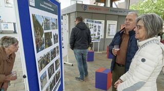 Wenige, aber interessierte Besucher schauen sich bei der Ausstellung auf dem Marktplatz die Bilderausstellung an.