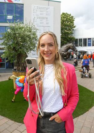 Mareike Sperling wirbt per Handy für das Maimarkt-Reitturnier.