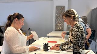 Die Auszubildende Anita Gojani (l.) übergibt Wahlunterlagen an zwei Wähler, die schon am Montagmorgen gekommen sind, um ihre Stimmen abzugeben.