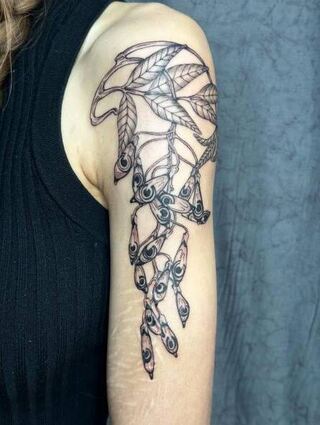 Ein filigranes Gud-Tattoo auf dem Oberarm einer Kundin.