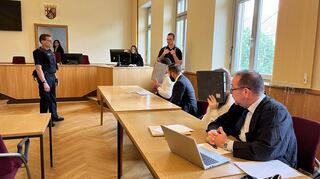 Wegen des großen Medienaufkommens halten sich die Angeklagten vor Prozessbeginn Aktenordner vors Gesicht.