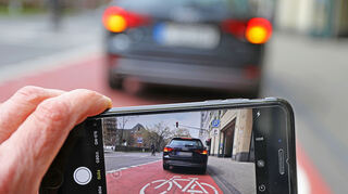 ILLUSTRATION - Auf einem Smartphone ist das Bild eines Autos zu sehen, das auf einem Radstreifen hält. Eine wachsende Zahl von Parksünden wird in Nordrhein-Westfalens großen Städten von Privatleuten gemeldet. (Zu dpa: "Privatleute gegen Parksünder: Zahl von Fremdanzeigen gestiegen") +++ dpa-Bildfunk +++