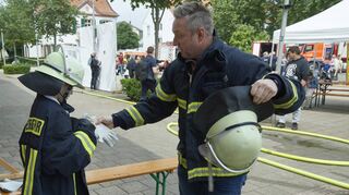 Ein Fest für Groß und Klein: Jonas (v.l.) und Dominik Hagenbucher ziehen Feuerwehrschutzanzüge an.