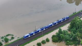 Ein Zug fährt über den höher gelegenen Bahndamm: Das Hochwasser des Flusses Schussen überschwemmt Teile von Meckenbeuren.
