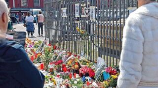 Auf dem Marktplatz ist das Alte Rathaus in Trauerbeflaggung und an den Einsatzwagen Trauerflor. Einsatzkräfte stehen bereit, während immer mehr Blumen abgelegt wurden.