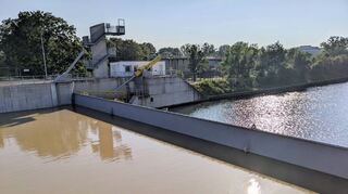 Der Höhenunterschied ist deutlich zu sehen: Links vom herabgelassenen Sperrtor das braune, aufgestaute Wasser, rechts davon der Kanal auf Normalhöhe.