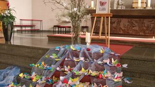 Schmetterlinge aus Papier liegen bei der Trauerfeier auf der Treppe vor dem Altar der St. Mauritius-Kirche in St. Leon-Rot.