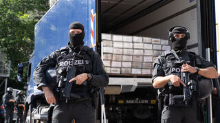 Polizisten sichern einen Polizei-Lastwagen mit sichergestelltem Kokain auf der Ladefläche.