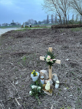 Dieses Holzkreuz mit Kerzen und Blumen steht an der Stelle, an der die junge Frau gefunden wurde.