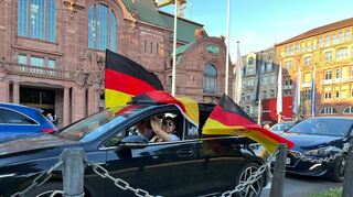 Eine Flagge ist nicht genug: Dieser Autofahrer in Mannheim nimmt lieber drei, um seine Begeisterung über den Sieg der Deutschen zu zeigen.