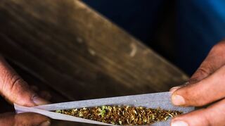 Ein mit Cannabis gefüllter Joint wird von zwei Händen gehalten.
