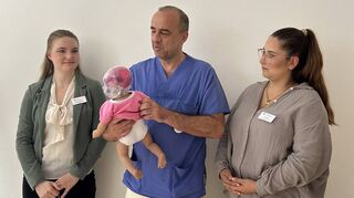 Oberarzt Paul Köhler und zwei Hebammen probieren die Schüttelpuppe aus. Die geschädigten Hirnregionen leuchten beim Schütteln der Puppe.