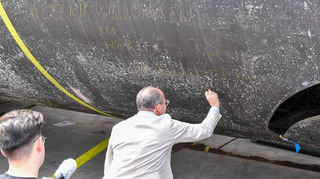 OB Christian Specht schreibt einen Willkommensgruß an den U-Boot-Rumpf.