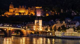 Abendliche Kulisse mit Schloss, Alter Brücke und einem unwirklich vom Metropolink-Festival illuminierten U-Boot in Heidelberg.