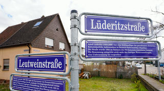 Mannheim: Straßenschilder mit der Aufschrift «Leutweinstraße» und «Lüderitzstraße», sowie Schilder zu Theodor Leutwein und Adolf Lüderitz mit Begleittexten stehen an einer Straßenkreuzung.