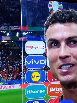 Cristiano Ronaldo beim Interview, links oben ist das Plakat zu sehen.
