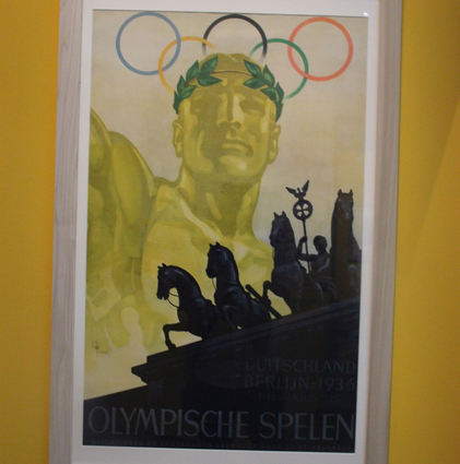 Plakat für die Olympischen Sommerspiele 1936 in Berlin: der Athlet mit martialischem Gesichtsausdruck und die Quadriga des Brandenburger Tores.