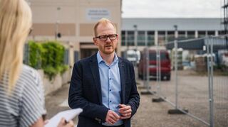 Johannes Kühn vom Eigenbetrieb Schule und Gebäudewirtschaft vor dem alten Schulgebäude, hinten ist die Riedhalle zu sehen.