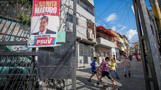 Ein Plakat der Regierung von Präsident Maduro hängt an einem Tor, während Kinder Fußball spielen. Maduro ist seit 2013 als Nachfolger von Hugo Chavez an der Macht.