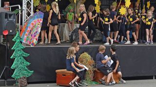 Die Ferienspielkinder zeigen das Musical Tabaluga: Hier ist der Sternentanz zu sehen. Vor der Bühne sitzen die Erzähler.