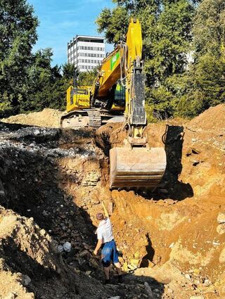 Klaus Wirth, Leiter Archäologische Denkmalpflege und Sammlungen der REM, weißt an der ausgegrabenen Mauer (links neben der Baggerschaufel) den Baggerfahrer ein, um weitere Teile freizulegen.