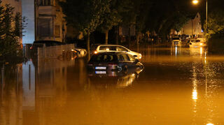 Hochwasser überflutet im Landkreis Karlsruhe eine Straße während ein Auto abgeschleppt wird.