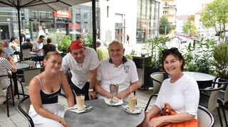 Sitzen im Café Fontanella auf dem Münzplatz mit einem Eiskaffee: Anik (v. l.), Martin und Iris mit Kellner Rino.