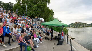 Ein Liedermacher spiel auf den Schlosstreppen am Rhein. An vielen Orten entstehen Pop-Up-Lokale am Fluss.