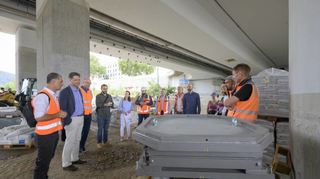 Bürgermeister Jürgen Odszuck (2.v.l.) besichtigt mit Tiefbau-Mitarbeitern die Brücke auch von unten, wo ein Brückenlager (vorne) auf den Einbau wartet.