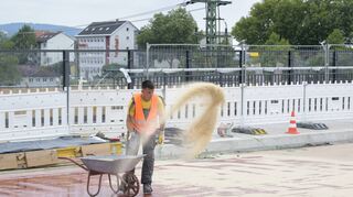 Ein Arbeiter bindet die rote Beton-Isolierschicht mit Sand ab: Stadteinwärts soll die Montpellierbrücke mit Ferienbeginn wieder befahrbar sein.