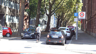 Mit dem E-Scooter unterwegs in der Karl-Ludwig-Straße zwischen parkenden und fahrenden Autos.