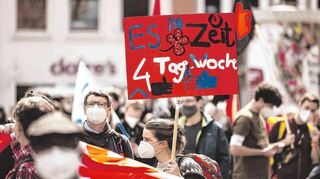 Eine Frau hält auf einer DGB-Kundgebung in Erfurt ein Schild zur Vier-Tage-Woche hoch. In der Diskussion um die Arbeitszeit treffen ganz unterschiedliche Meinungen aufeinander.