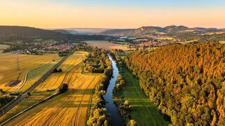 Panoramablick auf die Saale mit Leuchtenburg am Horizont.