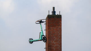 E-Scooter sorgen immer wieder für Ärger: Auf diesem Bild hängt ein Gefährt an einem Schornstein eines Supermarktes in Hannover.