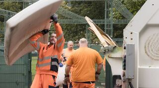 Umweltbürgermeister Raoul Schmidt-Lamontain (l.) packt kräftig mit an und stemmt eine mit Wasser vollgesogene Matratze in den Sperrmülltransporter.